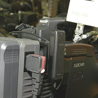 カムコーダーPDW-700に取り付けられたWi-Fiアダプタ「CBK-WA01」は収録中の画像をSDでPCに送信する（写真中央の青色LEDが点灯しているユニット）。