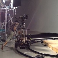 スタジオ（仙台市内）でのTVCM撮影風景：中央でジャンプする出演者と人力でカメラを動かすスタッフ。