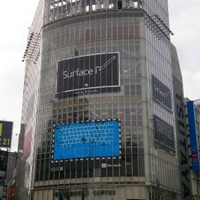 「QFRONT」の壁面に掲示された、「Surface」にペンで「P」という文字を書きかけた広告