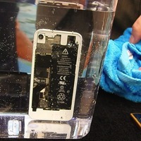 iPhoneの水没実験。iPhoneから泡が出ているので、内部に水が入っていることが分かる。透明で数ミクロンと薄いため分からないかもしれないが、電子部品にコーティングが施されているので、水が入っても安心