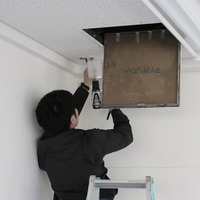 カメラの設置場所となる天井にドリルで穴を開ける工事スタッフ