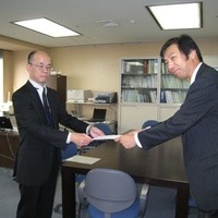 村上晃 総務省 北海道総合通信局無線通信部長（左）から免許状を受領する片岡浩一 UQコミュニケーションズ 副社長（右）