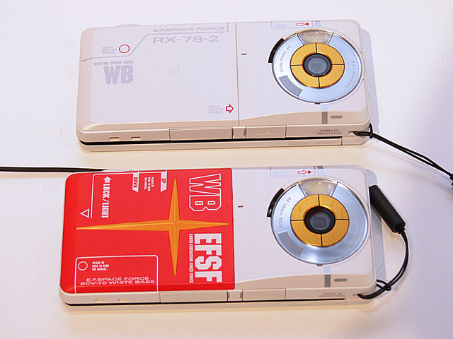 通常タイプの電池カバー（上）と、シールドをモチーフにした立体デザインの電池カバー（下）