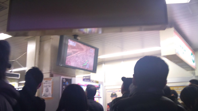 駅でテレビ映像を観る人々