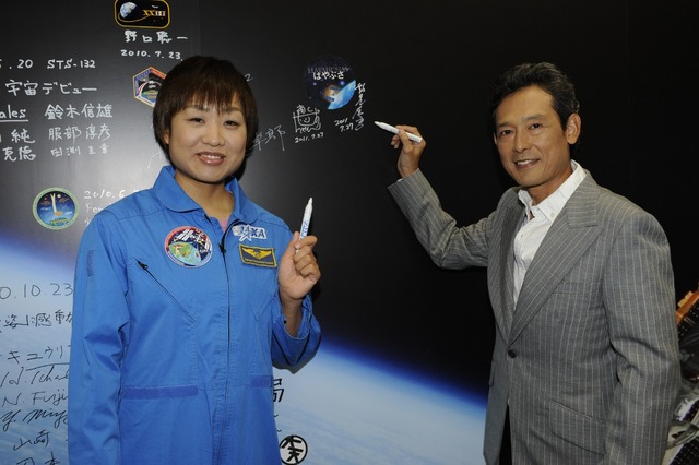鶴見さんとしずちゃんはJAXAの職員や、宇宙飛行士たちのサインが並ぶ広大な宇宙が描かれたパネルにサイン