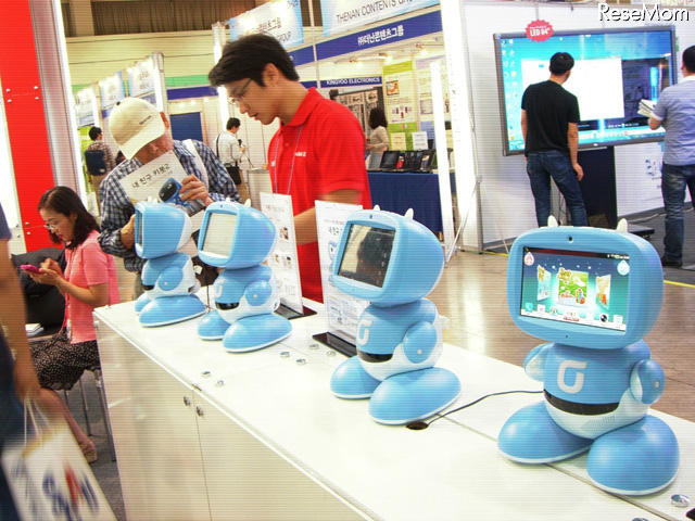 韓国最大手キャリアのKTが展示したKibotという幼児・小学生向け教育ロボット。子供とロボットが一緒に英語で歌って踊るコンテンツを提供しており、親が選んでダウンロードする。防犯カメラ、ボタン一つで保護者の携帯電話にテレビ電話をかける機能もある