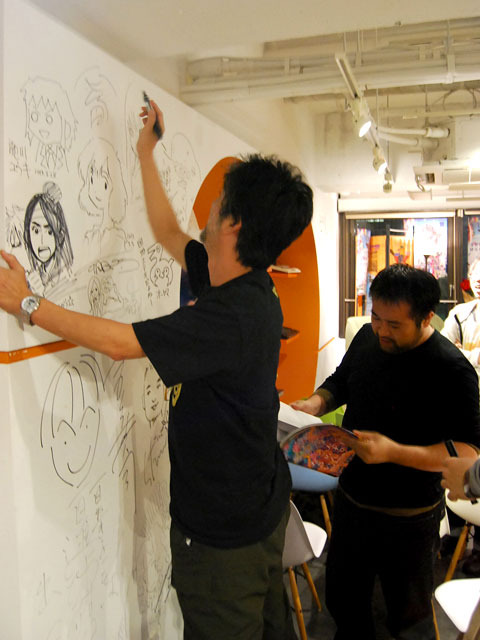 サインを壁に描く会田氏。