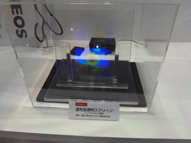 塗布型透明スクリーンも展示。ガラス上に、ナノダイヤモンドを使用した塗料を塗って、透明スクリーンとして利用できる。東京工業大学、ビジョン、ENEOSの3社による共同開発したもの