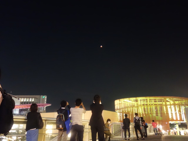 千葉県の海浜幕張駅前で月食を撮影する人々