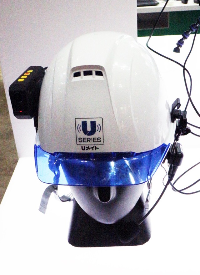 「Uメイト」をヘルメットに装着したところ。ヘッドセットもあるのでハンズフリーで作業に専念できる（撮影：防犯システム取材班）