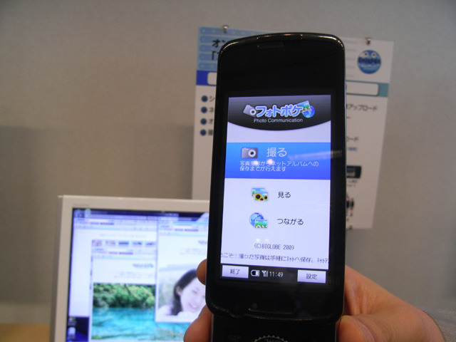 「フォトポケ」のデモ。ケータイで撮った写真はBIGLOBEサーバに自動アップロードされ、すぐに家族や友人に公開できる。Wi-Fi経由でデータを一括アップロードすることも可能。「フォトポケ」iアプリはドコモの「N-06A」にプリインストールされており、「これまで垂直統合型でやってきたキャリアが、他社サービスの専用アプリをプリインストールした国内初の事例」（飯塚氏）という。他機種でも、ダウンロードすれば利用可能