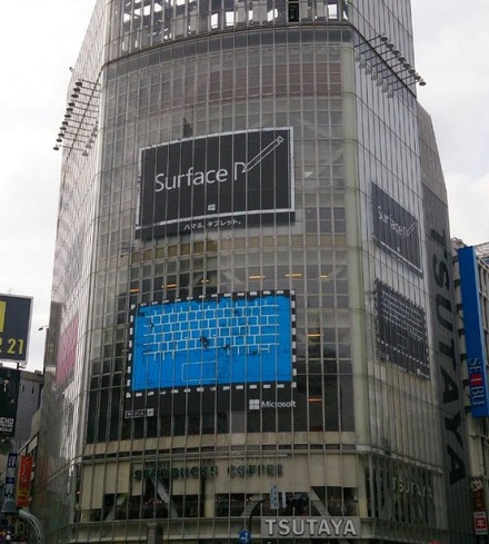 「QFRONT」の壁面に掲示された、「Surface」にペンで「P」という文字を書きかけた広告