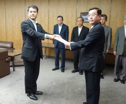 柴山昌彦総務副大臣から（左）から認定書を受領するUQコミュニケーションズ野坂章雄社長（右）