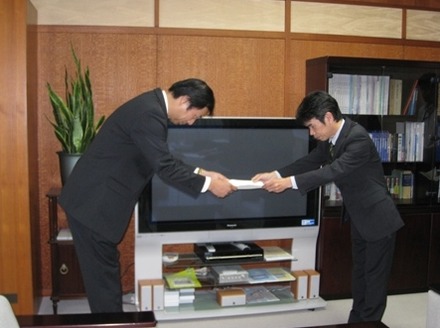吉武洋一郎 総務省 北陸総合通信局長（右）から免許状を受領する片岡浩一 UQコミュニケーションズ 副社長（左）